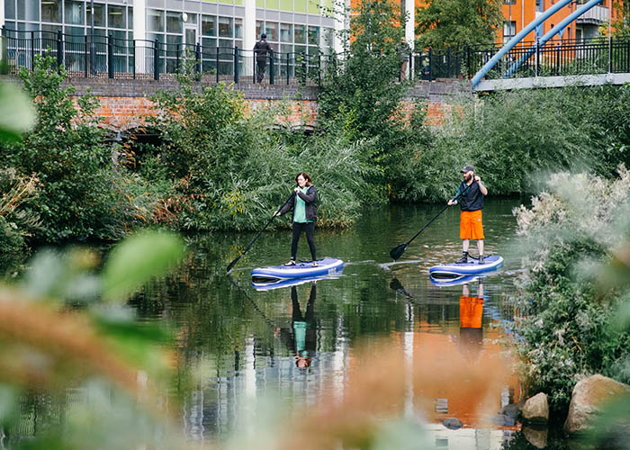 People paddling board in canal